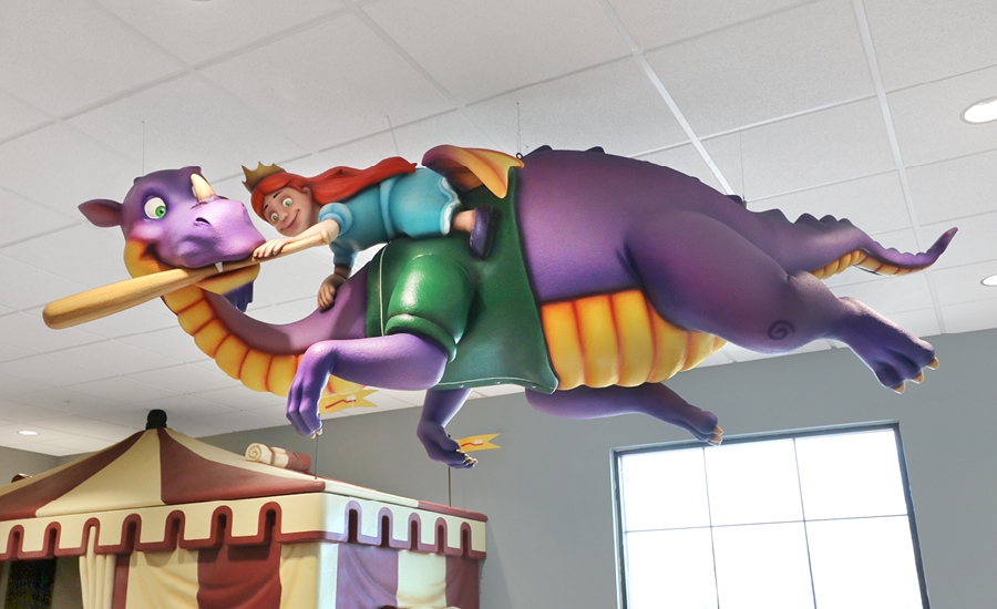 Ceiling suspended sculpture of a princess riding a purple dragon for a medieval tournament themed dental office.