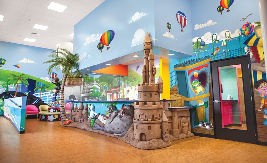 sculpted sandcastle reception desk and custom beach mural in pediatric dental office
