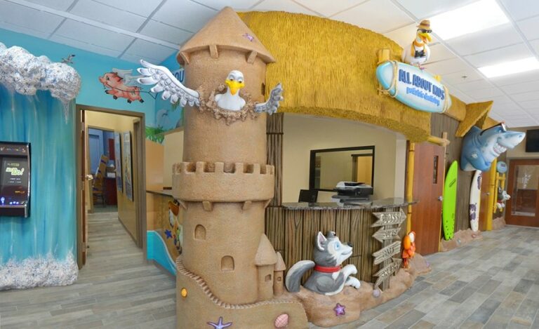 A beach-themed reception desk area with focus on a seagull bursting out of the top window of a large 3D sculpted sandcastle