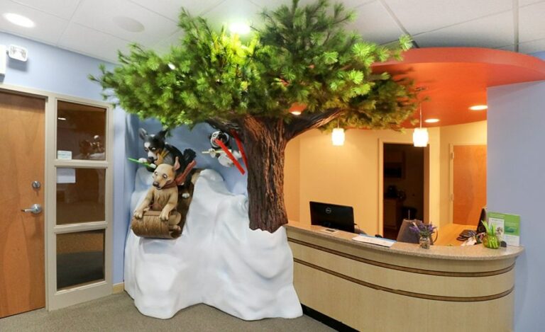 Winter-themed reception area featuring a sculpture of dogs sledding down a snowbank next to a tree.