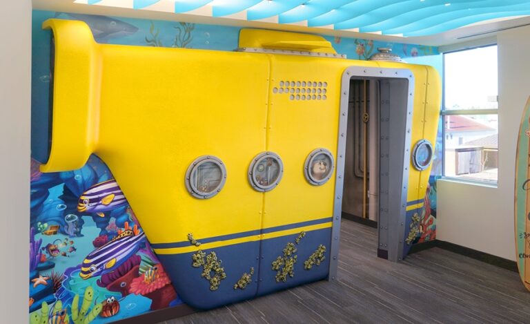 Entrance to a kid's play area with undersea-themed wall mural and sculpted yellow submarine wall cladding.