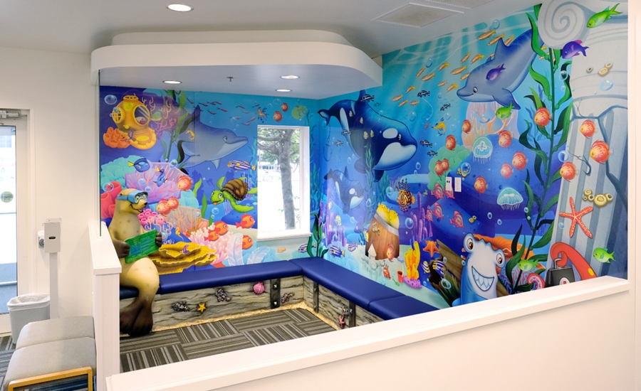 Under-water themed waiting area with cushioned bench seats and a 3D sculpted photo op seal wearing water goggles
