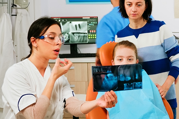 Dentist reviewing x-rays with patient and mother.