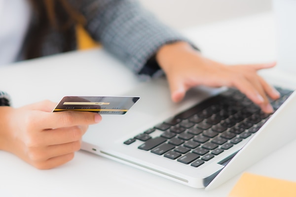Woman holding a credit card while typing in details in on the computer.