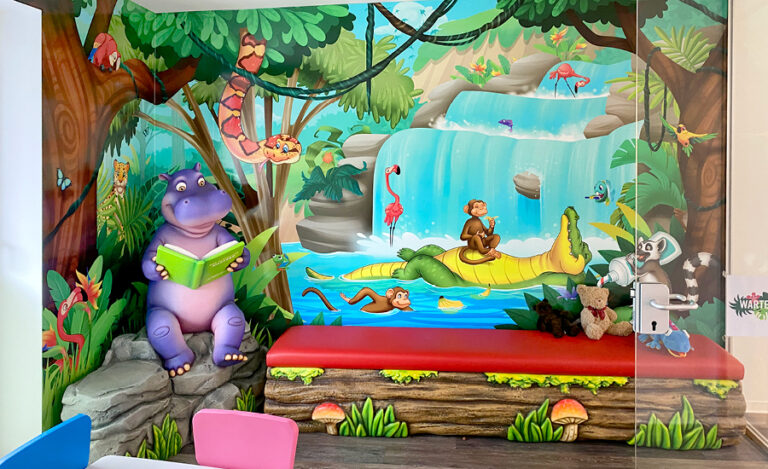Jungle themed waiting area with colorful wall murals, custom sculpted mossy log bench seat and hippo character seated on rocks.