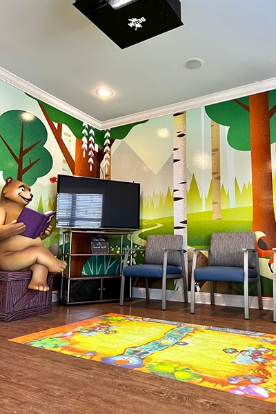 Woodland themed waiting room with contemporary wall murals and a 3D photo op bear.