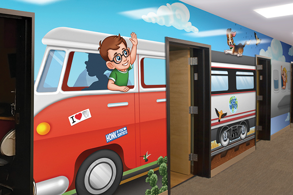 A colorful mural with city-themed decor shows a cartoon boy waving from a red van covered in fun stickers. The mural continues with a train, a dog, and clouds, brightening the hallway outside office doors.