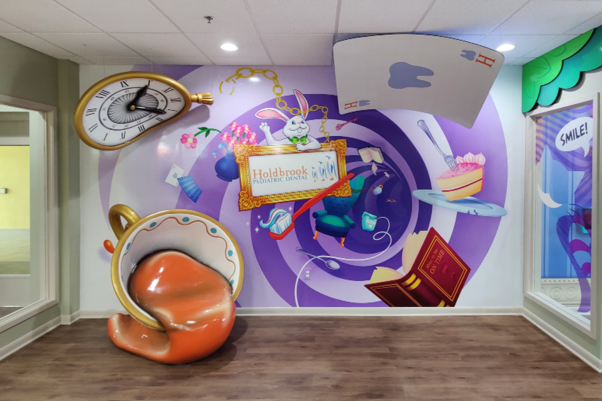 Dental office with 2D wall mural of spinning wonderland objects and signage mixed in with 3D sculptured warped clock, spilling teacup and bent card