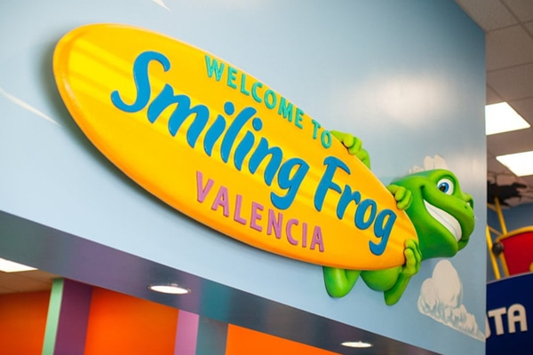 Custom 3D themed sign of a frog holding a surfboard that reads "Welcome to Smiling Frog Valencia".