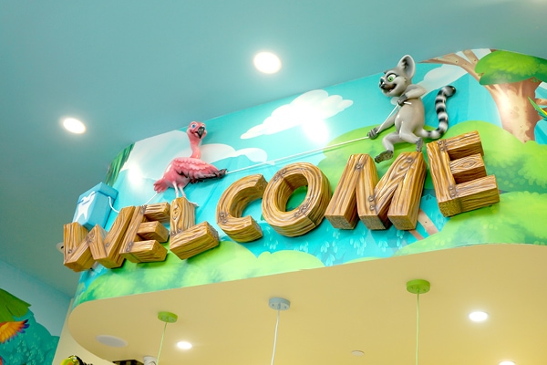 Custom "Welcome" sign with a flamingo and lemur playing tug of war with floss.