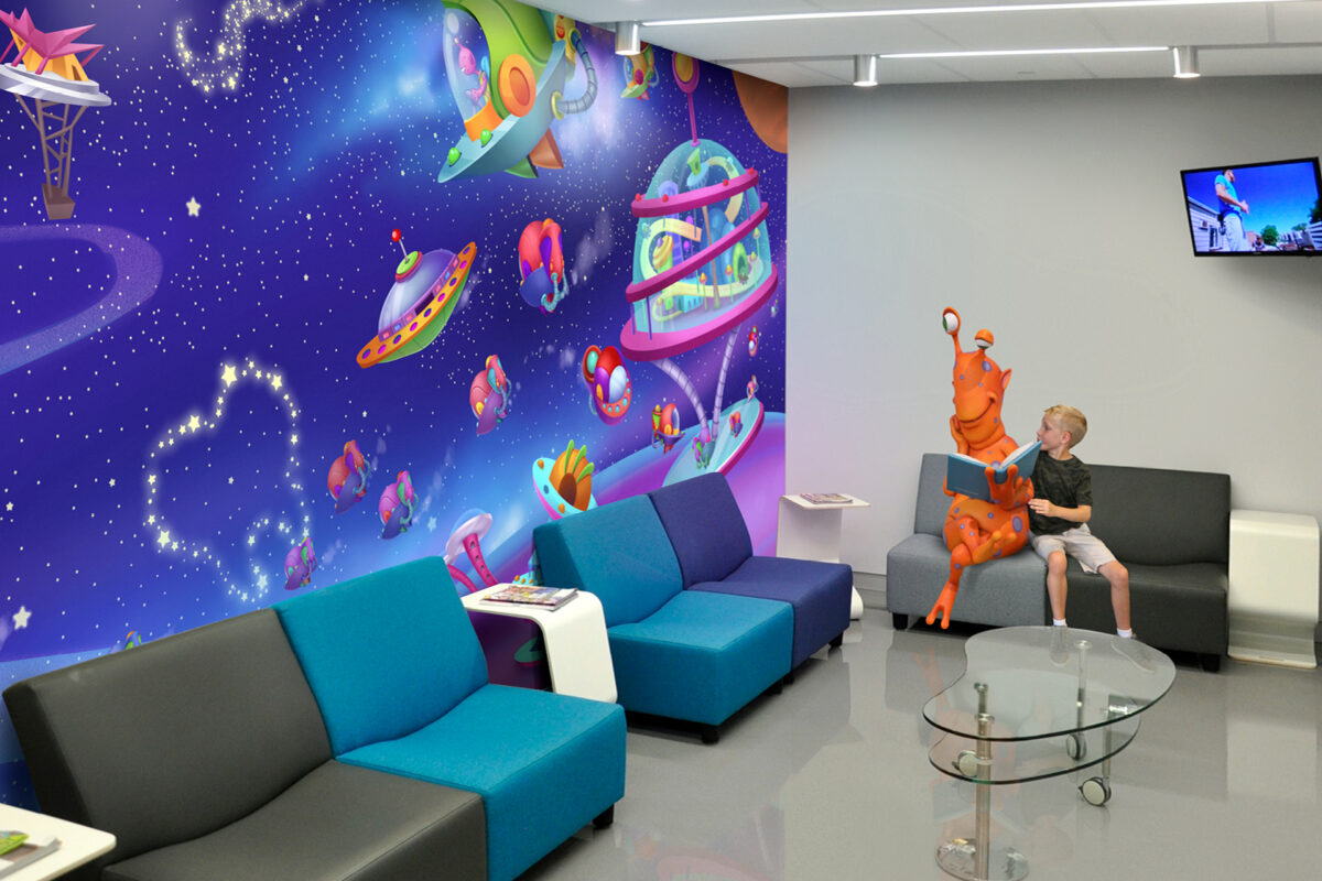 Before and after a themed environment transformation, a young boy sits next to an orange alien statue on a gray and blue couch in a modern room with a vibrant space-themed mural featuring cartoon spaceships and stars. A TV is mounted on the wall above.