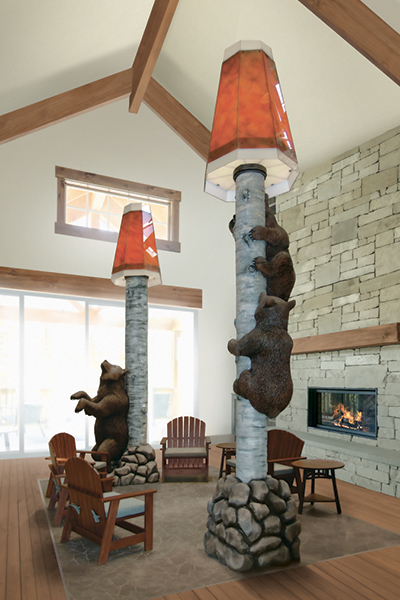 A cozy lodge interior showcases scenic fabrication with tall lamps styled as birch trees and realistic bear sculptures climbing the poles. Wooden chairs, a stone fireplace, and large windows complete this inviting themed environment.