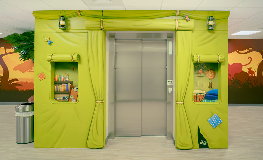 Elevator entrance framed by a green, safari-style tent structure creates playful hospital decor.
